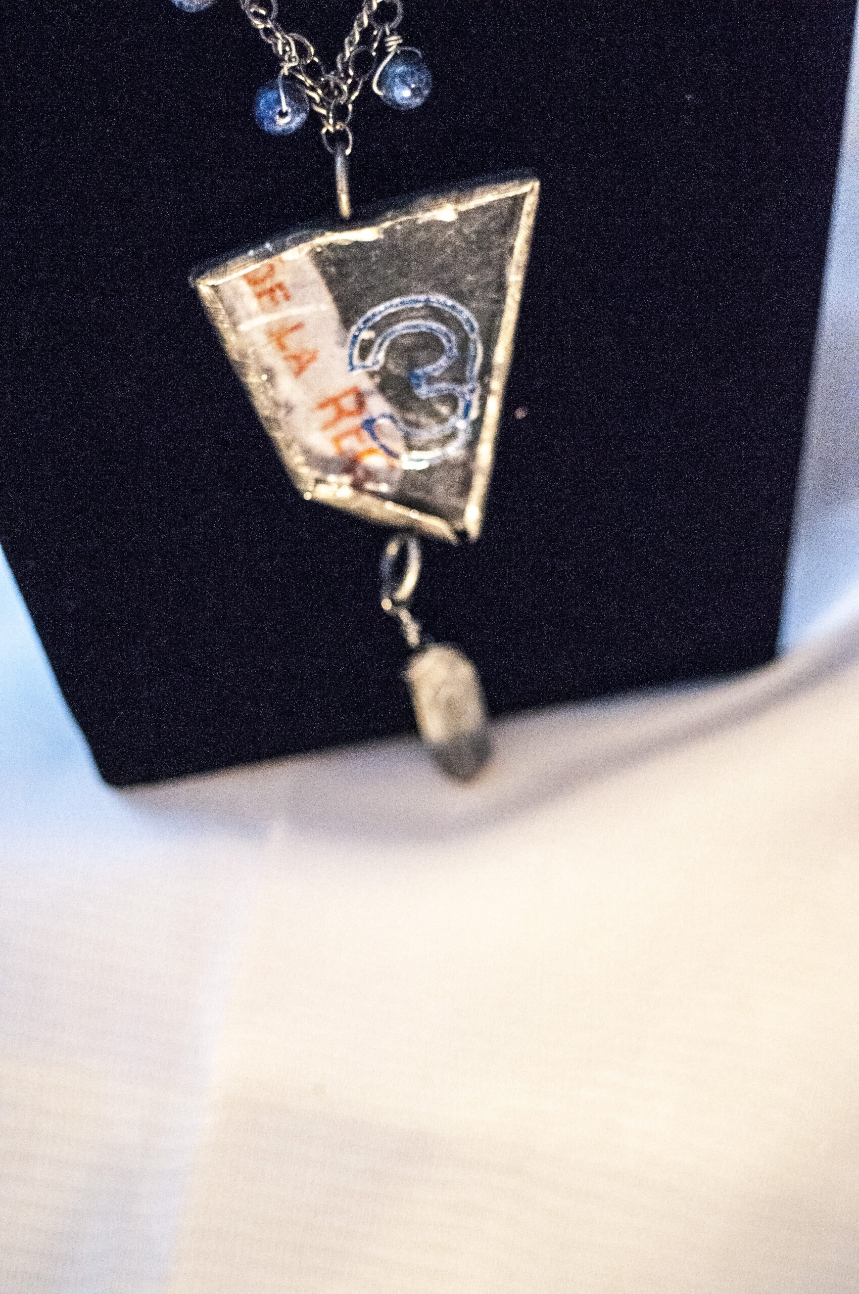 close up of glass pendant on long blue necklace